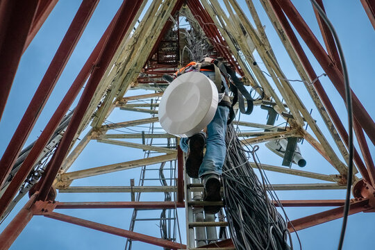 Unrecognized technician climbing up a telecommunication tower.
