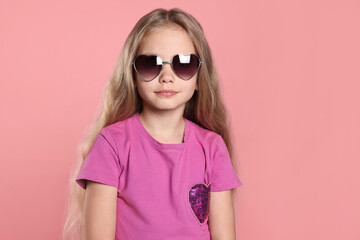 Girl wearing stylish sunglasses in shape of hearts on pink background