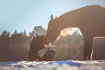 Horsemanship team scene: A young woman and her brown horse interacting and working as a team. Horse...
