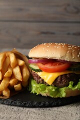 Delicious burger and french fries served on grey table, closeup