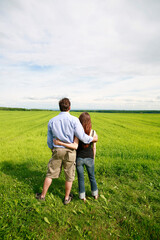 Naklejka na ściany i meble Rear view of young couple hugging and overlooking farmland.