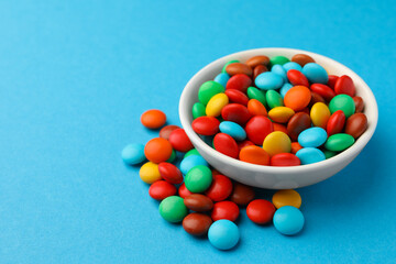 Tasty colorful candies on blue background, closeup. Space for text