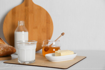 Jar with honey, milk, butter and bread served for breakfast on table. Space for text