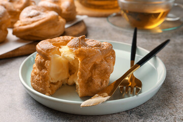 Delicious profiterole filled with cream on grey table, closeup