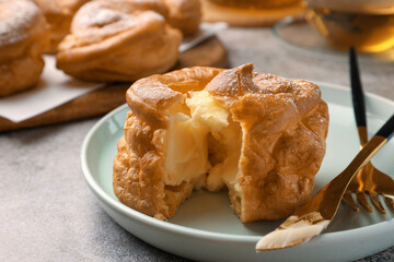 Delicious profiterole filled with cream on grey table, closeup