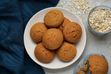 Delicious oatmeal cookies and flakes on light grey table, flat lay