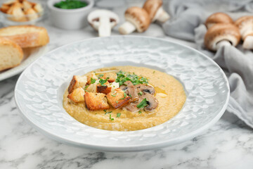 Delicious cream soup with mushrooms and croutons on white marble table