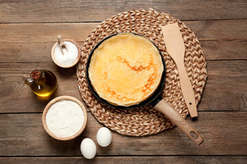 Delicious crepes and ingredients on wooden table, flat lay