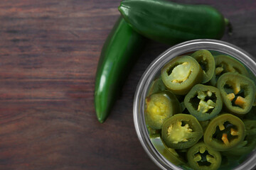 Fresh and pickled green jalapeno peppers on wooden table, flat lay. Space for text
