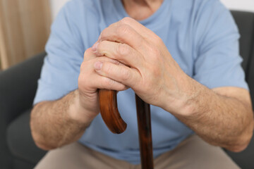 Senior man with walking cane at home, closeup