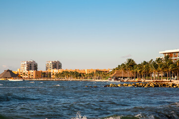 Naklejka premium Picturesque view of sea coast, palm trees and distant resort on sunny day