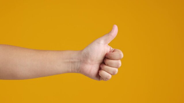 Hand giving thumbs up on yellow background