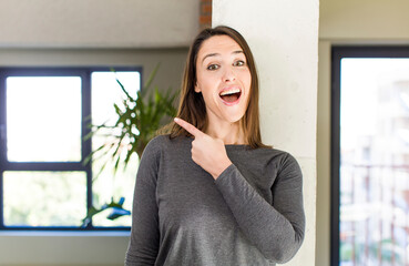 Fototapeta premium young adult pretty woman looking excited and surprised pointing to the side and upwards to copy space