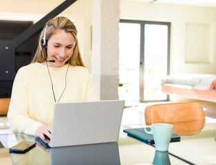 young adult pretty blonde woman working at home. teleconmmuting concept