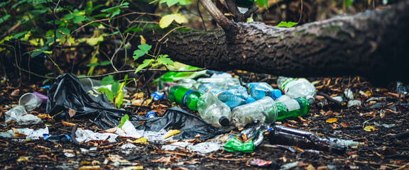 Garbage pile in forest among plants. Toxic plastic into nature everywhere. Rubbish heap in park among vegetation. Contaminated soil. Environmental pollution. Ecological issue. Throw trash anywhere. - obrazy, fototapety, plakaty
