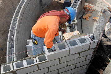 Mason installing a structural block retaining wall