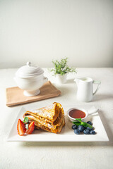 Sweet pancakes with berries and honey on a white plate, selective focus