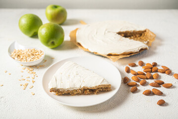 Piece of apple cake on a white plate with almonds and green apples.