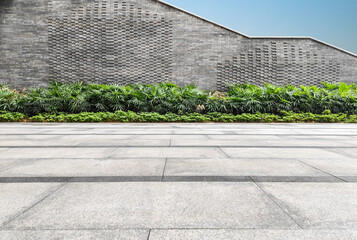 Empty square floor and modern stone wall with green plant in the park