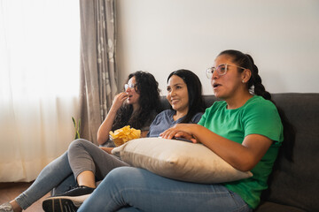 Obraz premium Latin womens on the couch eating french fries