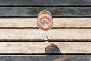 A glass of rose wine on a wooden table in sunlight top view - 569403756