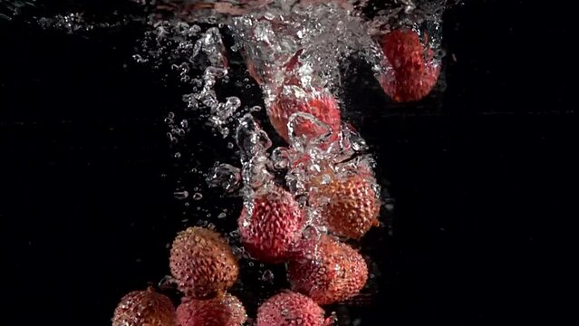 Super slow motion of falling lychee fruit into splashing water. Lemonade cooking concept. Filmed on high speed cinema camera, 4k 1000 fps.