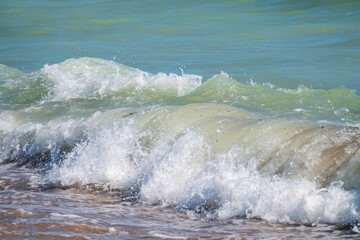 Splashes of water and foam against the sea on a sunny summer day