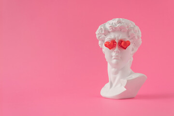 Trendy love composition made of fake statue of David's head with red glass hearts on the eyes on...