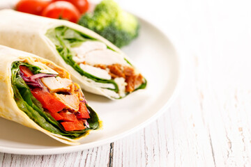 Fresh chicken fajita wrap sandwiches on white plate.