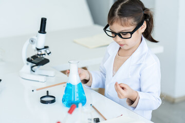 Children girl schoolgirl, Hand holding flask while doing chemistry experiments, in science class, girl used magnifying glass, peering into mouth glass bottle, where light smoke was coming out.