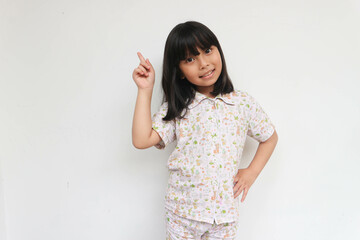 Portrait of child girl wearing pajama with finger pointed up. Little kid in pose has idea isolated on grey background. Success, bright idea, creative ideas and innovation technology concept