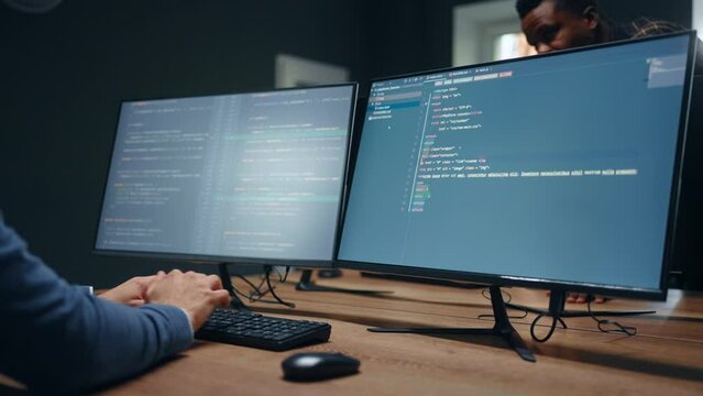 data scientist writing code on double display computer in office of IT company, closeup of screen
