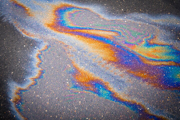 Colored texture of oil products on the asphalt in the rain.