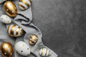 Easter eggs are painted with gold paint on a gray linen background.