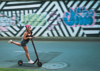 brunette woman smiling fast driving an electric scooter in the city