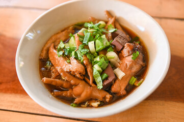 chicken soup with chicken leg feet and wings in red soup bowl and vegetable spring onion - stewed with chinese herbs