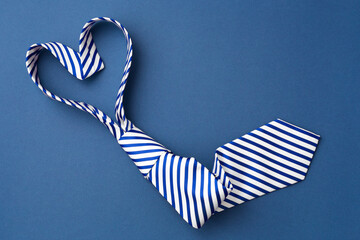 Necktie in heart shape on blue background - obrazy, fototapety, plakaty