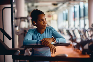 Pensive African American female athlete in gym looking away.