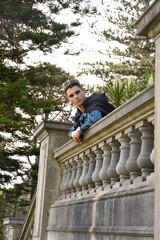 portrait of handsome man wearing fantasy medieval prince costume with golden crown and romantic silk shirt.  sitting on a stone balcony in a historical castle location background.