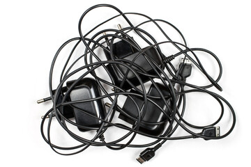 Chargers with tangled wires on a white background. Wired chargers for phones.