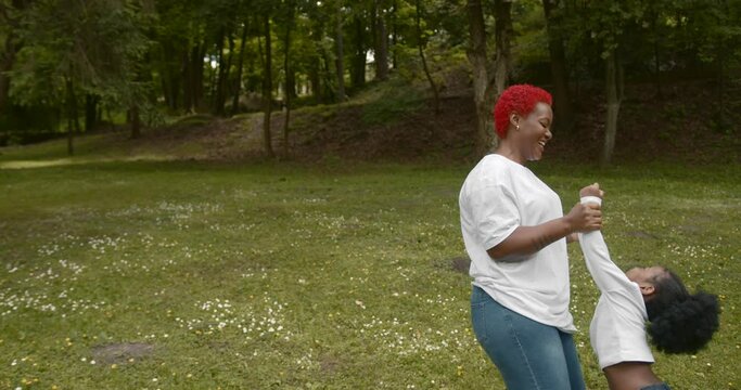 Black woman playing wit her daughter outdoors in summer