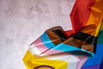 Rainbow LGBTQIA flag made from silk material on concrete background with copy space for your text....
