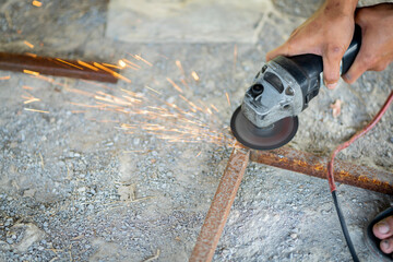 A blacksmith is using a sharpener, sparks come out while cutting.