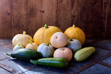 Fresh vegetable marrow and gourds are piled on table in barn.