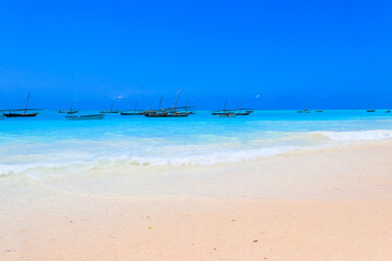 Obraz premium View of tropical sandy Nungwi beach and traditional wooden dhow boats in the Indian ocean on Zanzibar, Tanzania