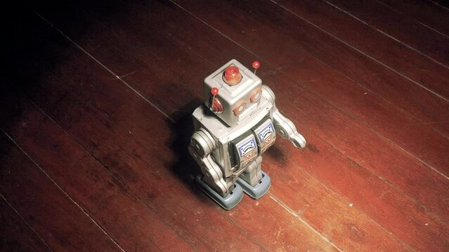 Retro tin robot toy slow dancing on a wooden floor