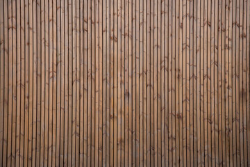 brown natural wooden background with wall of small vertical wood boards on a horizontal facade