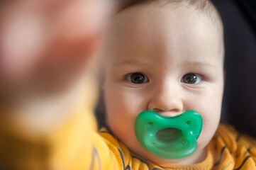 Cute baby boy stretches out his hand towards the camera in front and tries to reach and touch the toy. Front angle view