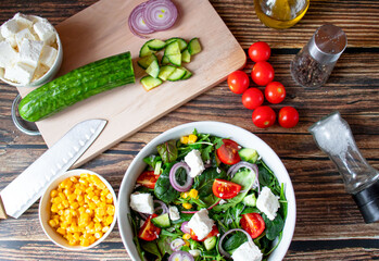 A green vegan salad made from a mix of green leaves and vegetables. On a wooden background