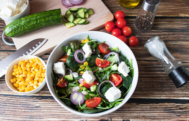 A green vegan salad made from a mix of green leaves and vegetables. On a wooden background
